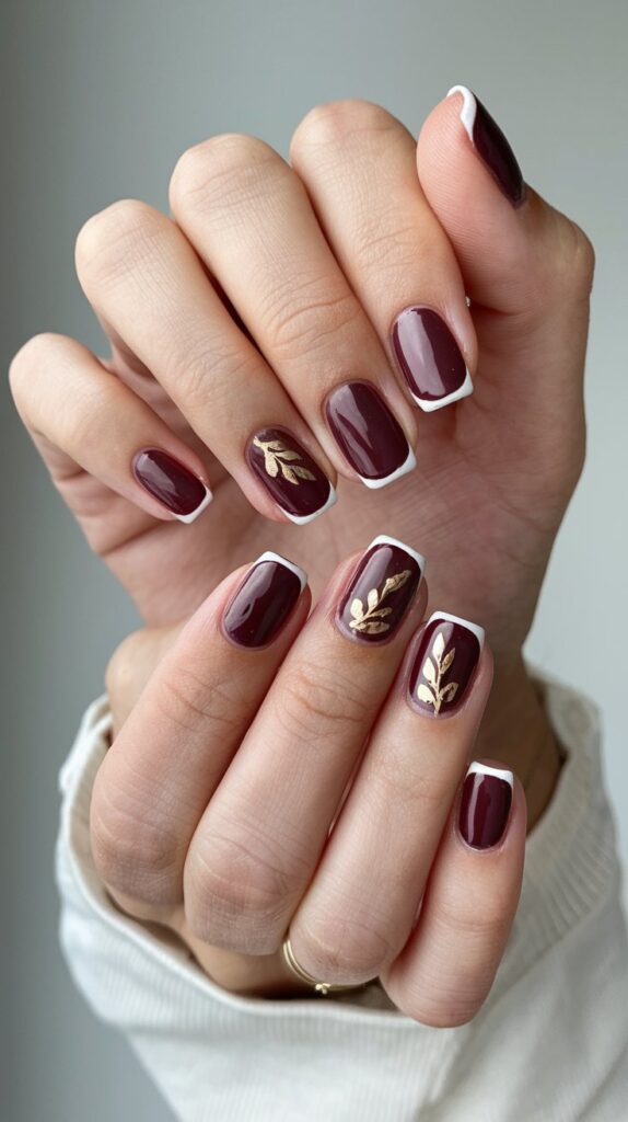 woman's manicured hand with a plum french nail design with gold leaf for fall